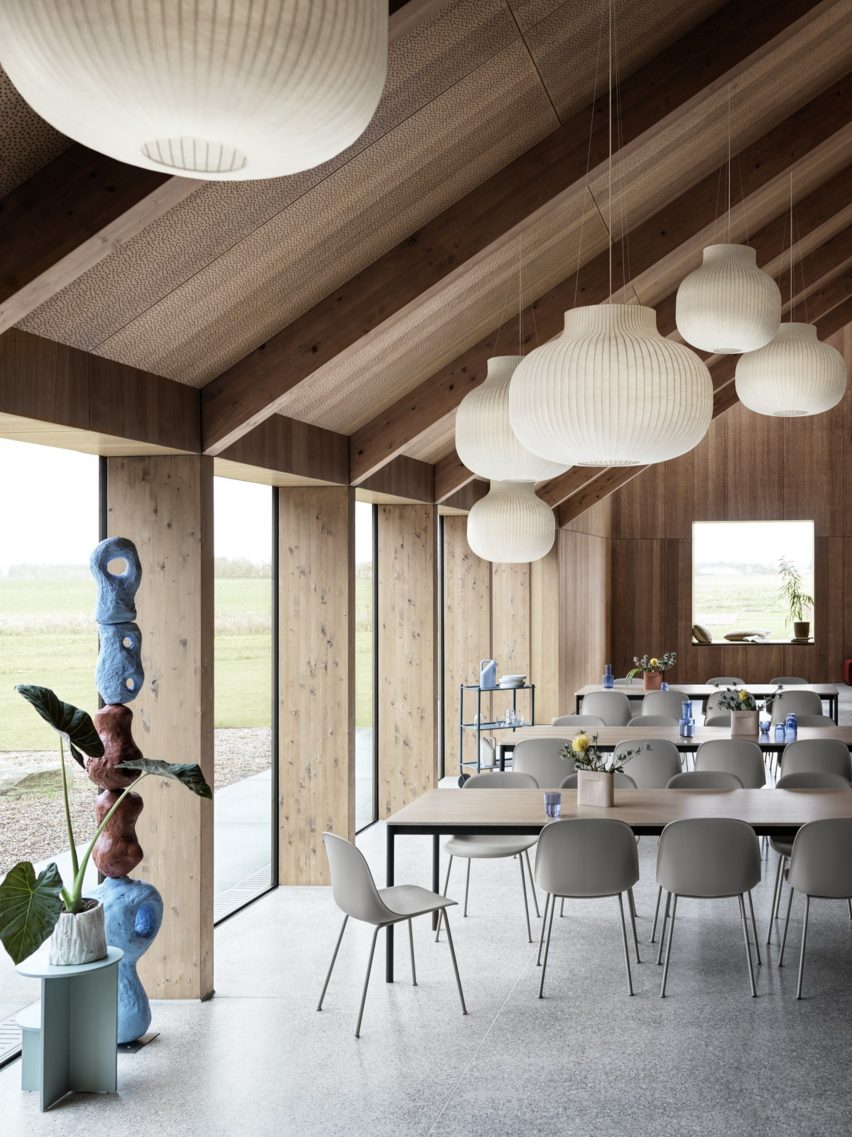 A group of Muuto Fiber Chairs in grey surround an oak veneer table in a minimalist interior
