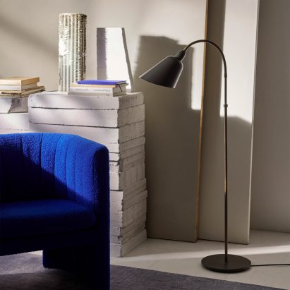 Grey Bellevue lamp standing next to a bright blue upholstered chair