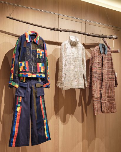 Garments are suspended from branches at Bethany Williams: Alternative Systems
