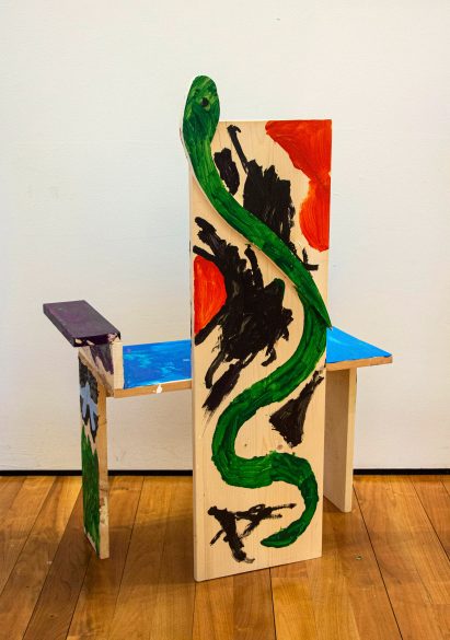 Child-made chair with snake detail cut out of pinewood plank
