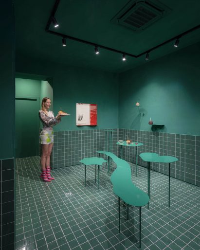 Woman holding pastry in sea green back room of of Madrid's Cara Mela pastry shop designed by Case Antillón