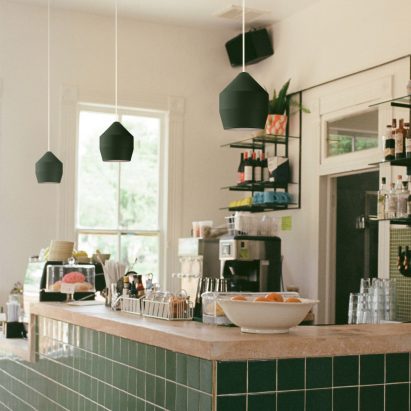Three green Hoxton pendants by Innermost used over a green tiled bar