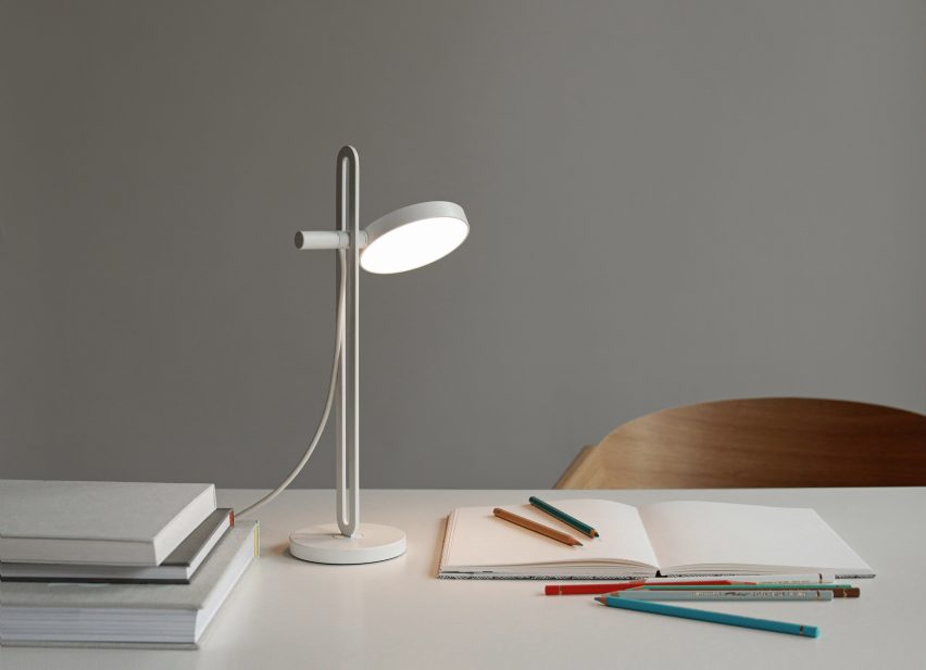 White Echo lamp by Caussa on a desk with paper pads and pencils