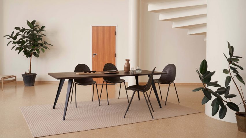 Four Eternity chairs around a wooden dining table in a cream painted room with plants
