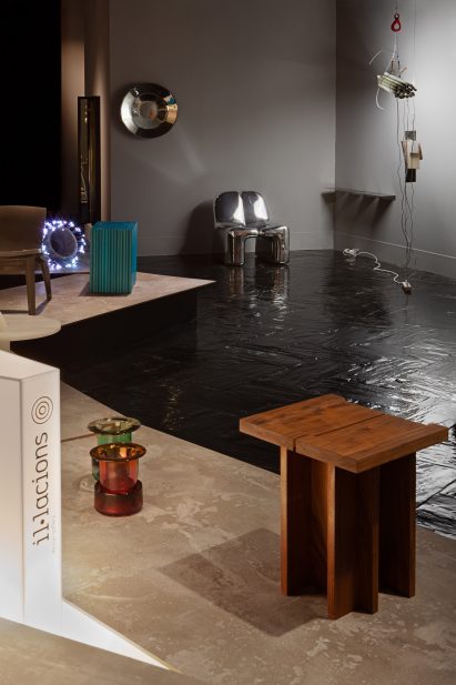 Wooden side table is photographed beside glass vessels at Inferences/Inferencias