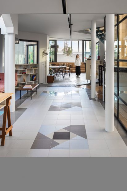 Girl walking down hallway with geometric tiles and white pillars