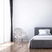 A chair by Michael Graves next to a bed