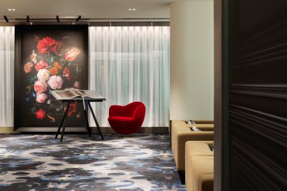 Red armchair next to book stand in Schiphol VIP centre