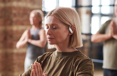 A photograph of a lady using the earbuds while doing yoga