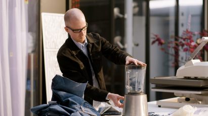 A photograph of man placing jeans in a mixer