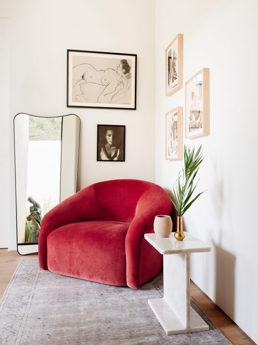 red plush sitting chair with mirror and art