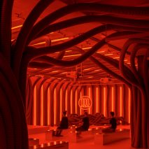 People sitting in Everywhere and Nowhere installation filled with PVC pipes and red light by Pareid