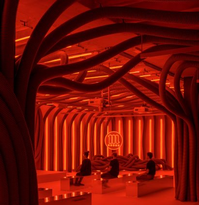 People sitting in Everywhere and Nowhere installation filled with PVC pipes and red light by Pareid