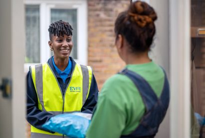 Delivery person in Evri vest delivers a package to a person at their front door