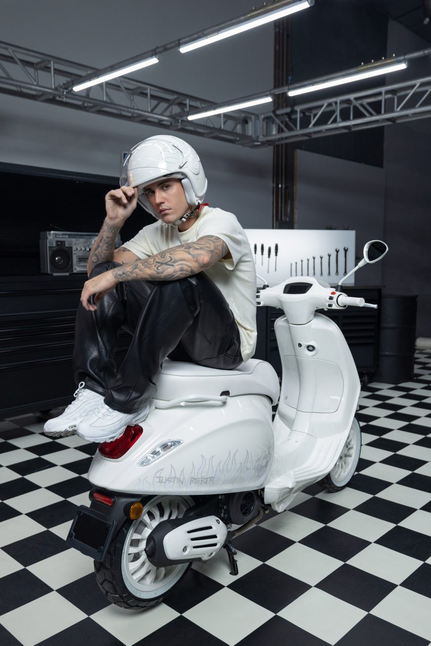 Justin Bieber in a white helmet sitting on a scooter he designed for Vespa