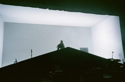 A rapper crouching on stage on a house