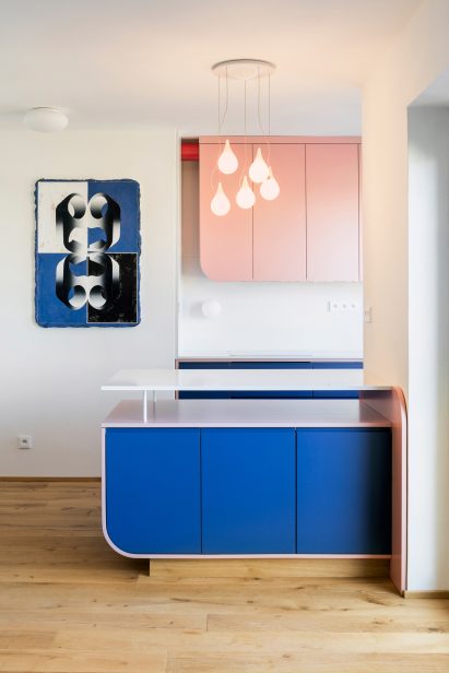 Sixty-Nine by Vladimír Houdek hung on the wall next to a baby pink and royal blue kitchen
