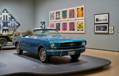 A shiny blue car being exhibited in a gallery