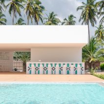 A blue pool is positioned opposite the beach house