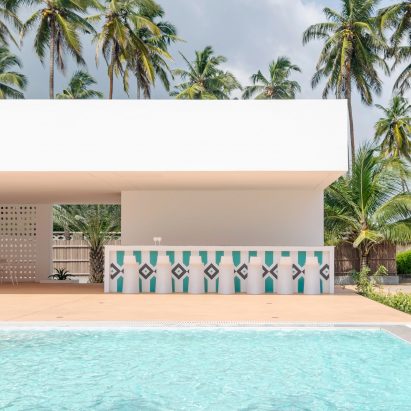 A blue pool is positioned opposite the beach house