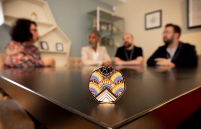 Pride in London members sitting behind a Pride 50p coin