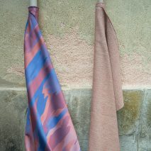 A pale pink roll of fabric next to a blue and rose roll of fabric