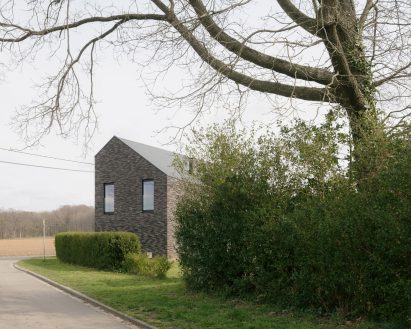 Brick house appearing from behind greenery