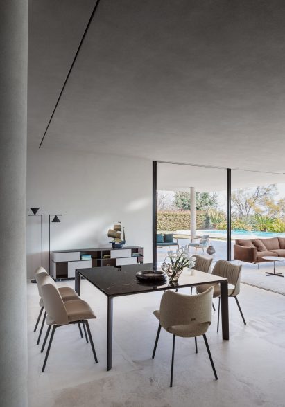 Nice chairs by Poltrona Frau around the Homey table in a concrete room with floor to ceiling glass window
