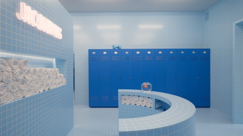 A Jacquemus lit up sign is pictured above a collection of towels