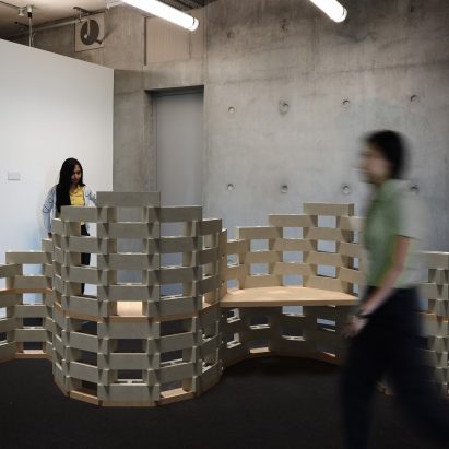 Two people walking past a fence-like installation
