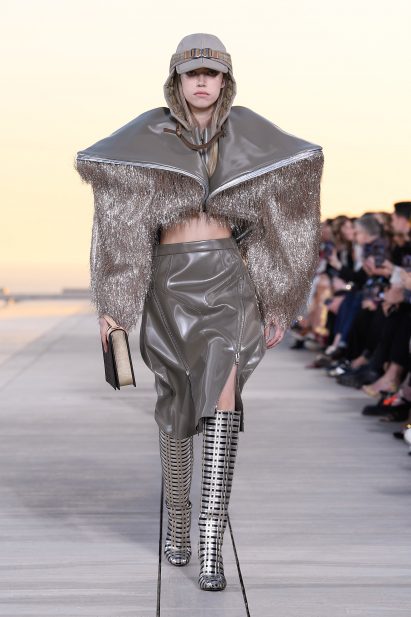 Model is pictured wearing a sculptural golden bolero
