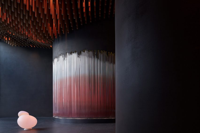 Photograph showing dark cement interior with curved walls and illuminated glass rods