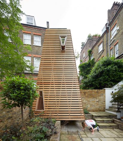 Child crawling under wooden playspace