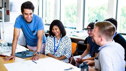 Four students round a table attending the RCA Architecture Summer School course