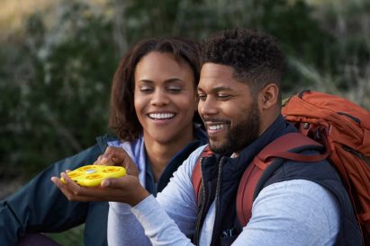 A couple on a hiking trip play with the yellow Snapchat drone