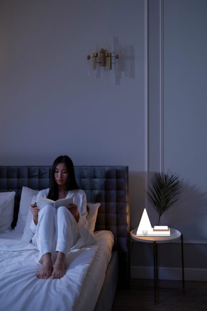A photograph of a person reading with a light next to them