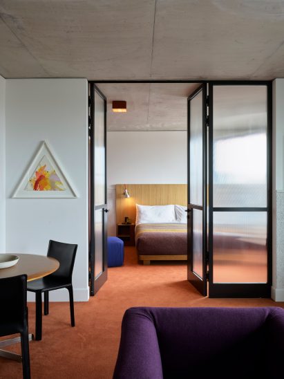 Guest bedroom with orange carpet in hotel by Flack Studio