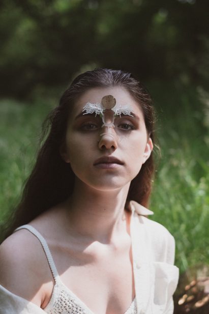 Model wearing a white jewellery piece placed on the bridge of the nose