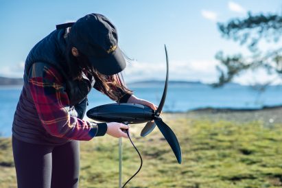 Person sets up the Shine Turbine on a grassy field beside a lake