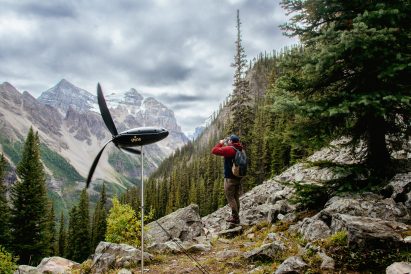 Portable wind turbine set up on the side of a mountain with a hiker standing nearby