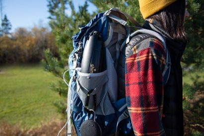 Shine Turbine folded up into a water bottle-like package and tucked into the side of a backpack