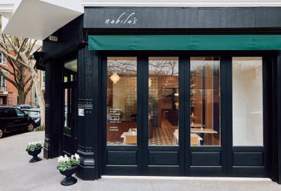 Black timber-clad building with green awnings in Brooklyn