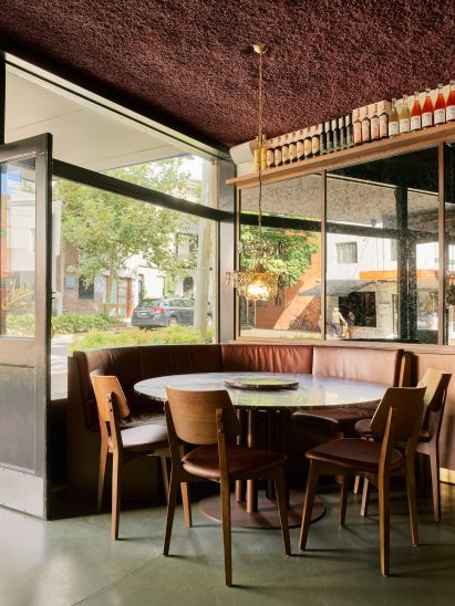 Seating area with stone table and wooden chairs in bar in Surry Hills, Sydney designed by Luchetti Krelle