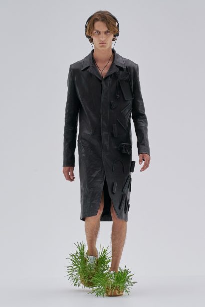 A model is wearing a coat with tech accessories attached to it at Loewe Spring Summer 2023