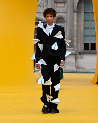 Image of a model wearing a suit with leather paper planes attached at Louis Vuitton Spring Summer 2023 show