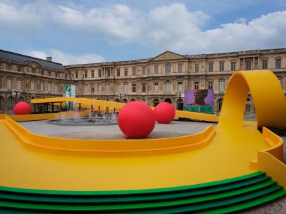 A yellow path winds through a courtyard at the Louvre at the Louis Vuitton Spring Summer 2023 show