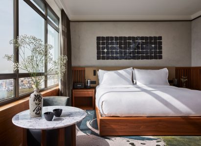 Bedroom with wooden bed frame in hotel designed by Rockwell Group