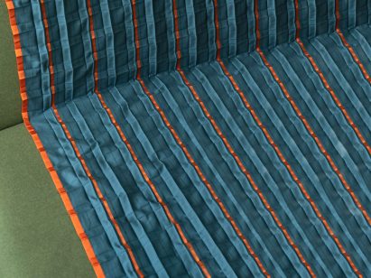Close-up on the solar-powered heated blanket showing orange ribbon covering the conductive yarn