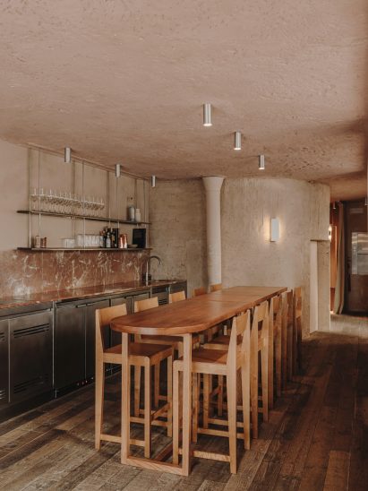 Wooden counter surrounded by bar stools in Madrid restaurant by Plantea Estudio