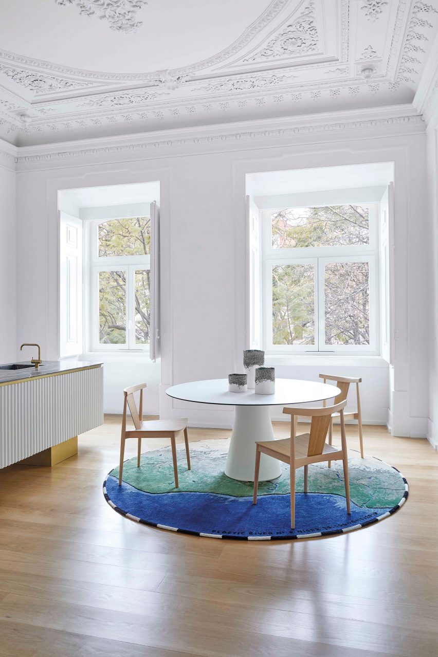 High-ceilinged room with round rug beneath round dining table and chairs